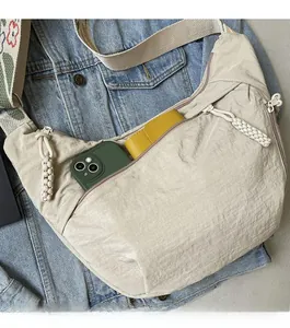 Detail of beige nylon crossbody bag featuring wide floral strap and front zipper pocket