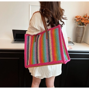 Close-up of rainbow striped crochet tote bag with brown leather handles worn by a model