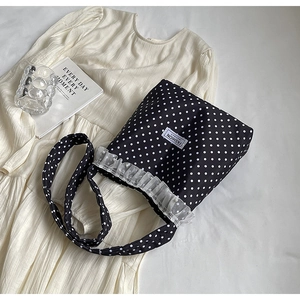 Dettaglio della borsa a secchiello in nylon a pois neri con pizzo bianco e perle