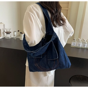 Detail of dark blue denim tote bag featuring decorative orange circular stitching