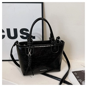 Détail du sac seau noir en cuir verni craquelé avec logo métallique élégant