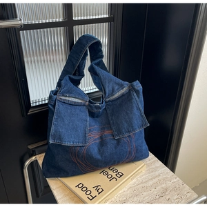 Detail of dark blue denim tote bag with spiral stitching and functional front flap pockets