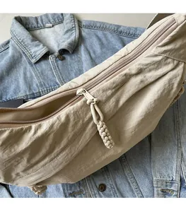 Detail of smooth zipper and knotted cord puller on a beige nylon crossbody bag