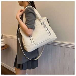 Detail of a large off-white leather tote bag with silver zipper on a shoulder strap
