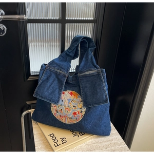 Détail de la broderie dragon sur sac cabas en denim bleu avec anse nouée unique