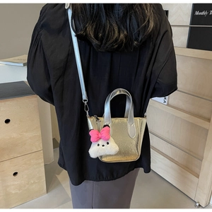 Detail of silver metallic mini bucket bag with cute plush bunny charm on shoulder strap