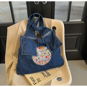 Détail de la broderie dragon sur un sac cabas en denim bleu marine pour femme