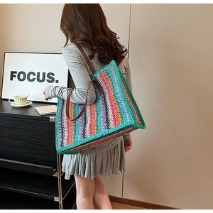 Detailed close-up of a handmade colorful striped crochet tote bag with leather straps