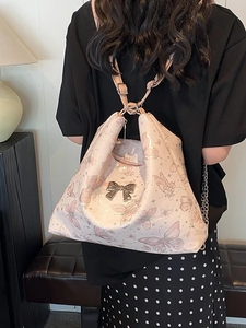 Pink butterfly print tote bag with metallic bow detail shown on a model's shoulder