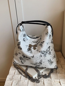 Butterfly print hobo bag with silver chain strap and metal bow on a stone display