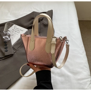 Detail of rose gold tote bag with cracked texture leather and cream handles