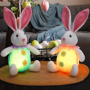Detail of glowing plush Easter bunnies with LED lights and sunflower accents on woven mat