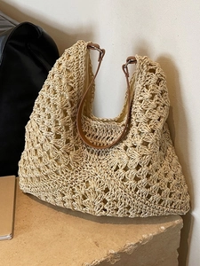 Large beige woven straw tote bag with brown leather straps for summer beach vacations
