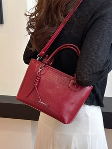 Sac seau rouge foncé en similicuir avec détails argentés et pendentif à pampilles tressé