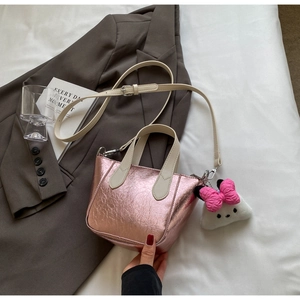 Detailed shot of metallic pink wrinkled leather mini bag with soft plush bow charm