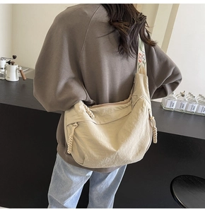 Detail of beige nylon hobo bag with floral embroidery strap and drawstring detail