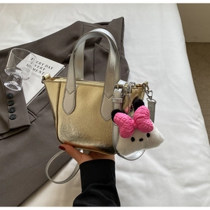 Detail of metallic color-block mini bucket bag with plush doll charm and bow