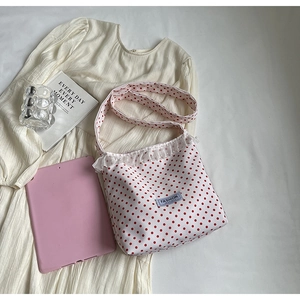 Dettaglio della borsa in nylon a pois con bordo in pizzo e decorazioni di perle