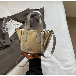 Detail of mini gold and silver bucket bag with cracked texture and silver hardware