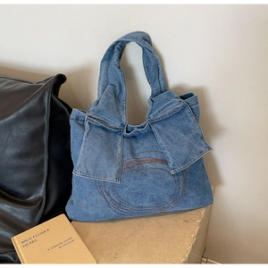 Detail of blue washed denim tote bag with bow handles and circular stitch patterns