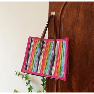 Detail of colorful crochet tote bag with striped texture and brown leather handle