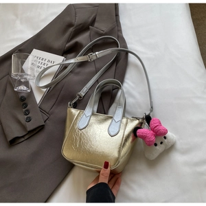 Detail of metallic gold bucket bag with silver handles and pink plush bow accessory