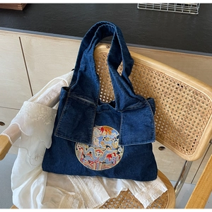 Vue détaillée du sac cabas en denim bleu foncé avec broderie de dragon sur chaise rétro