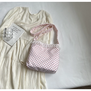 Dettaglio borsa a secchiello bianca a pois rossi con pizzo e perle decorative