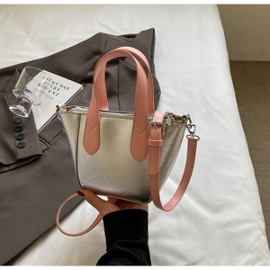 Detail of silver metallic bucket bag featuring pink handle and silver zipper hardware