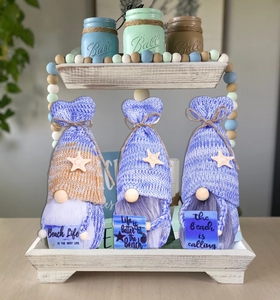 Nautical gnome figurines on a tiered tray with summer beach life slogans and starfish