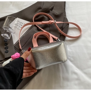 Detail of silver metallic bucket bag with pink handles and plush heart charm decoration
