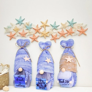 Detailed view of ocean-themed knitted gnomes featuring starfish and beach slogan signs