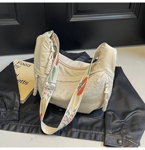 Detail of beige nylon crescent bag featuring a floral embroidered wide shoulder strap