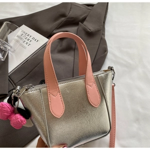 Close-up of silver crackle leather handbag with pink strap and fluffy bow charm