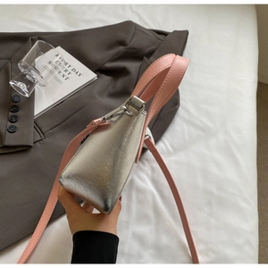Detail of silver textured handbag with pink top handle and metallic silver buckle