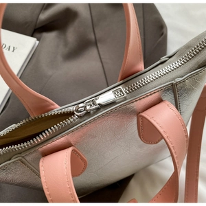 Close-up of silver crackle texture fabric and pink leather handle with metal zipper