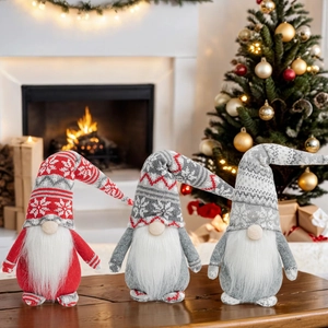 Three Christmas gnomes with snowflake knit hats set against a cozy fireplace and tree