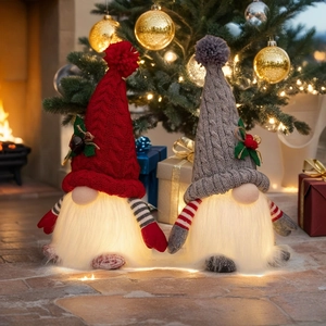 Close-up of lighted Christmas gnomes with knit hats and glowing white beards on a cozy mantel