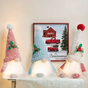 Close-up of three knitted Christmas gnomes with warm white LED lights for holiday decor