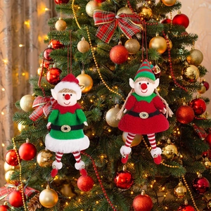 Christmas elf plush ornaments hanging on a decorated tree with warm festive string lights