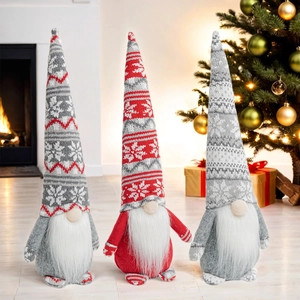Detailed view of three knitted Christmas gnomes featuring snowflake patterns by a fireplace