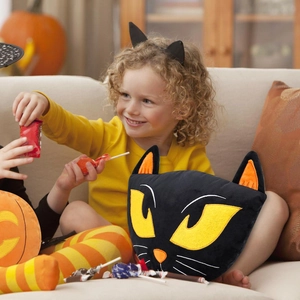 Cuscino peluche gatto nero di Halloween con occhi gialli in un ambiente domestico caldo