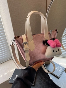 Pink metallic texture bucket bag with white handles and cute plush charm handheld view