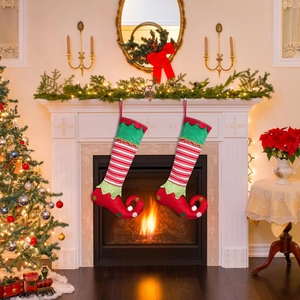 Detail of red and green striped Christmas elf stockings hanging by a cozy fireplace