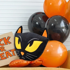 Dettaglio del cuscino di peluche gatto nero di Halloween con occhi gialli e orecchie arancioni