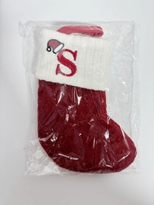 Detail of red knit Christmas stocking featuring embroidered letter S and mini Santa hat