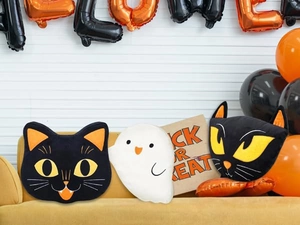Tre cuscini di peluche di Halloween con gatto nero e fantasma su un divano giallo
