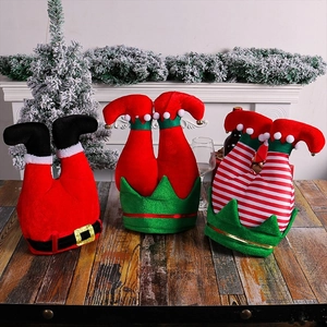 Three-piece Christmas elf and Santa plush leg decorations on a festive wooden table