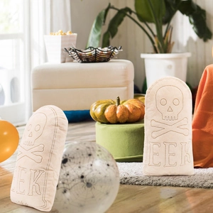 Halloween tombstone pillow with skull embroidery and EEK text in a festive living room