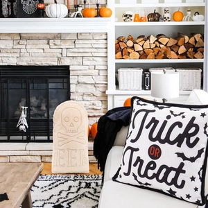 Close-up of Halloween Trick or Treat pillow and tombstone decorative cushions on a fireplace